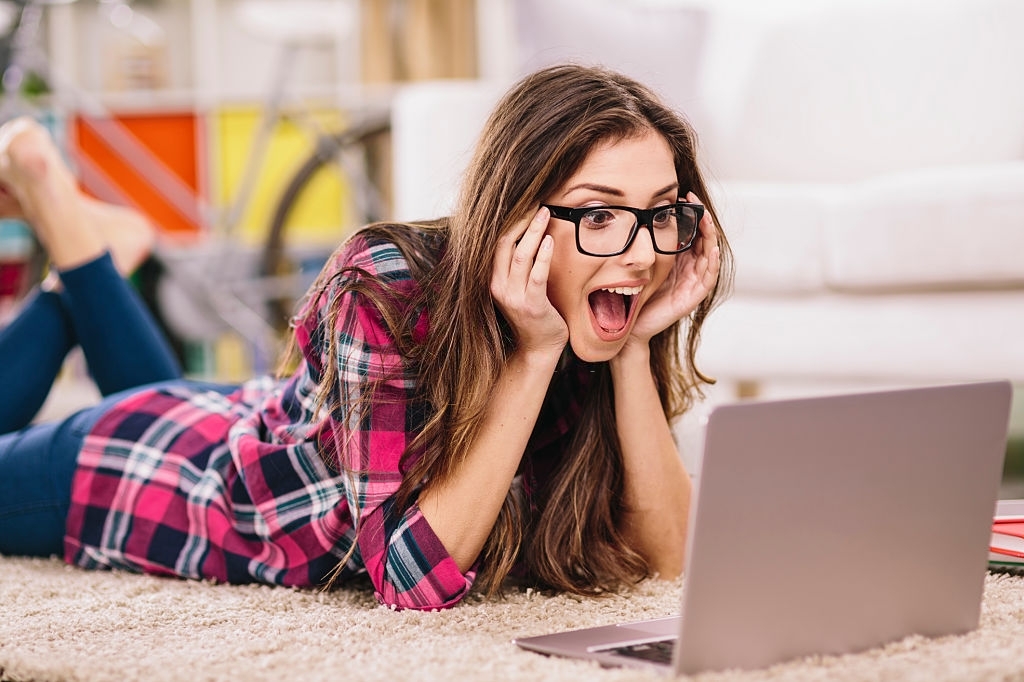 Woman seems surprised looking at her laptop.